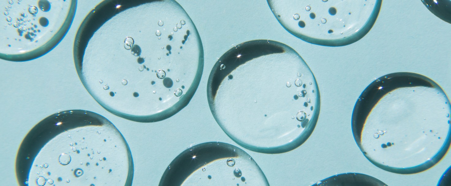 Drops of natural moisturizing gel on blue background. Flat lay, top view. Skincare beauty product