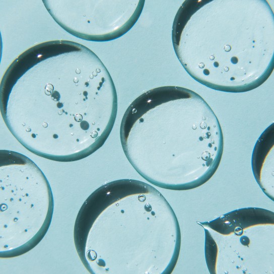 Drops of natural moisturizing gel on blue background. Flat lay, top view. Skincare beauty product