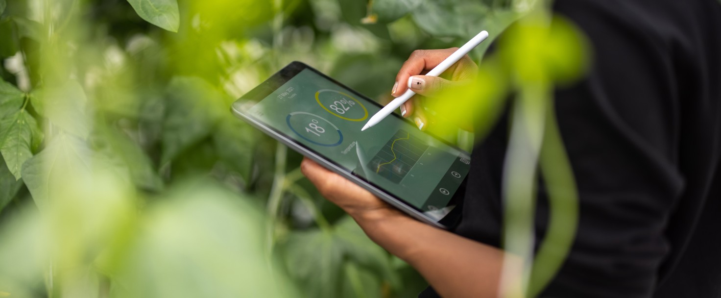 Cropped shot of a woman agronomist using digital tablet for analysis of plantation. Woman updating plants growth on digital tablet app in garden center.