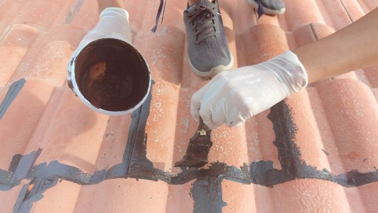 Craftman is putting waterproof sealer to roof tiles