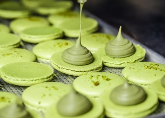 Process of making fresh handmade macaroons in restaurant kitchen. Colourful macaroons cookies on baking trays