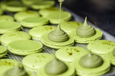 Process of making fresh handmade macaroons in restaurant kitchen. Colourful macaroons cookies on baking trays.