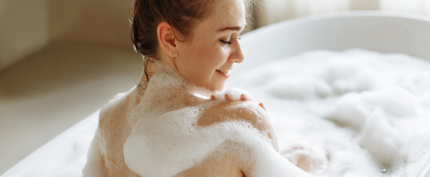 Back view of a young beautiful woman enjoying a bubble bath