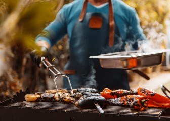 Unknown man preparing BBQ food on an outdoor grill
