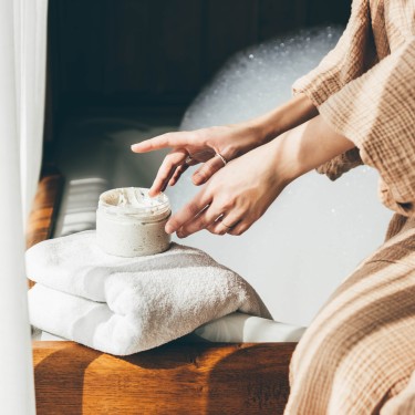 Woman taking care of her skin. Young woman in bathroom applying cream.