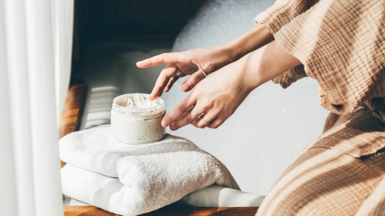 Woman taking care of her skin. Young woman in bathroom applying cream.