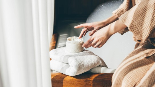 Woman taking care of her skin. Young woman in bathroom applying cream.