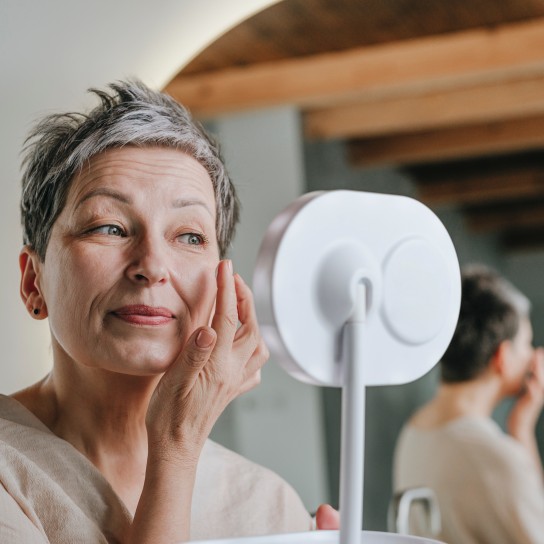 Woman applying face cream looking in mirror