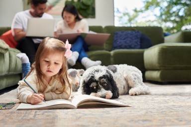 little girl colouring in with her pet dog