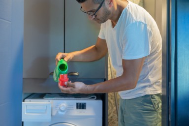 Man Pouring Liquid Detergent Gel Into Washing Laundry Machine At Home