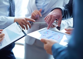 Unrecognizable business people examining financial reports and analyzing business growth