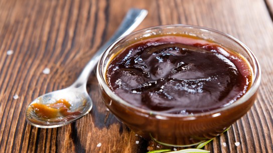 Barbeque Sauce with Tomatoes, Smoked Salt and fresh Herbs (on rustic wooden background)