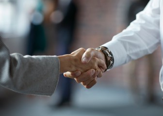 Close-up of businessman & businesswoman making handshake at convention