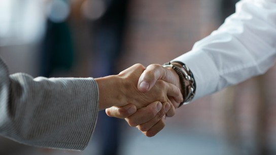 Close-up of businessman & businesswoman making handshake at convention