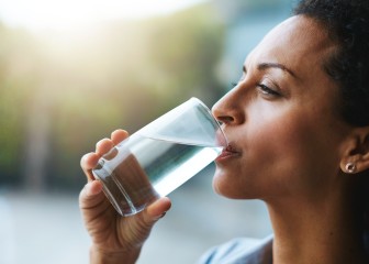 Shot of a woman drinking a glass of water at home