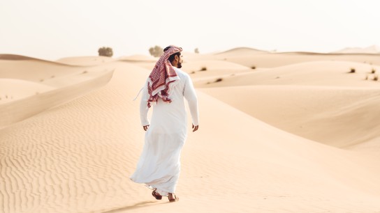 arabic man walking alone in the desert
