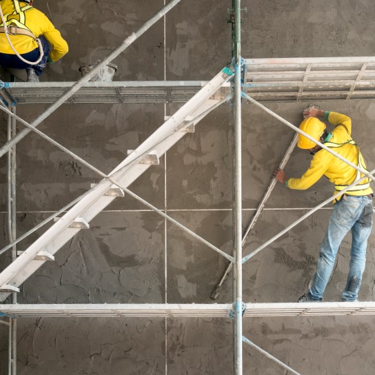 Construction worker plastering cement on concrete block wall
