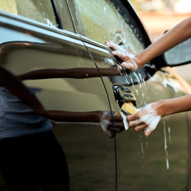 Shot of an unrecognizable young child washing their parent's car outside during the day