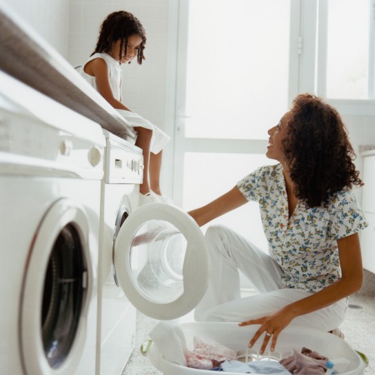 Mother and daughter paughing while doing laundry