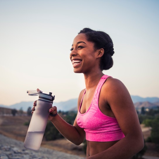 Happy female runner holding water bottle