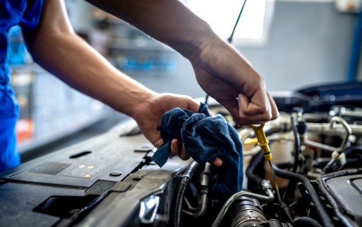 Photo of Unrecognizable male mechanic measuring the oil level of an engine at an auto shop. Mechanic checking the oil level in a car service garage. Repairing engine at a service station. Car repair."r"n.