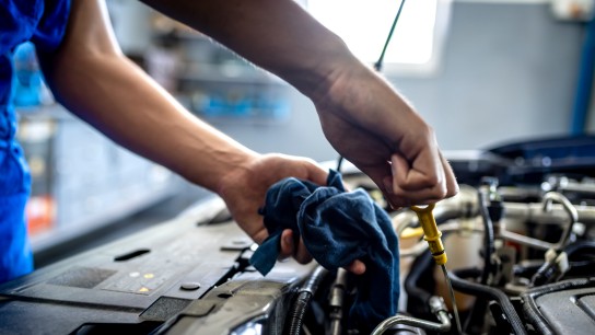 Photo of Unrecognizable male mechanic measuring the oil level of an engine at an auto shop. Mechanic checking the oil level in a car service garage. Repairing engine at a service station. Car repair."r"n.