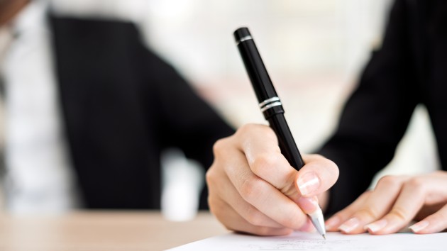 Close-Up Of Business woman signing a business contract On Table background with business man