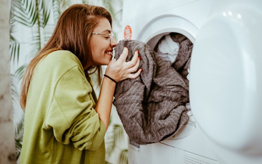Young woman takes laundry out of the washing machine