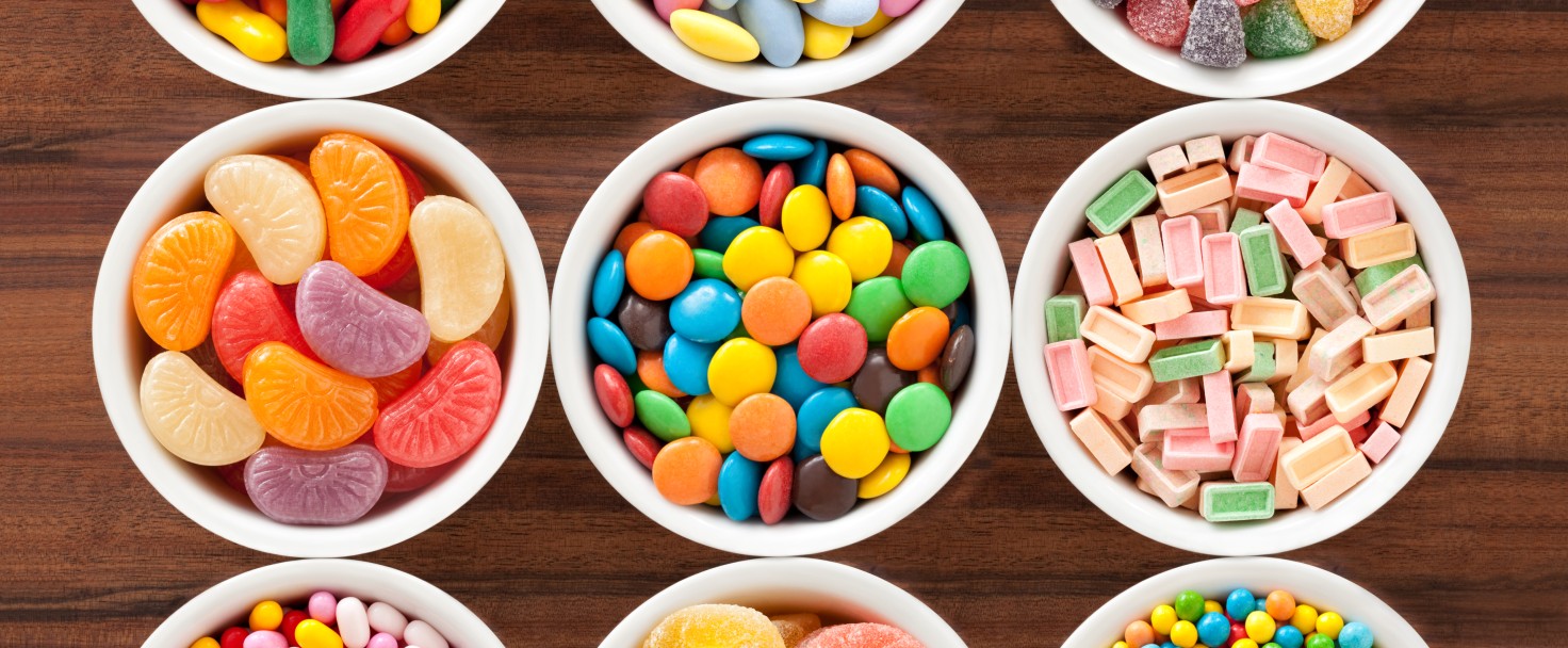 Top view of nine bowls with different types of multicolored candy