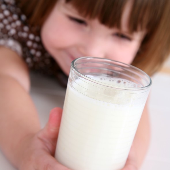 Cute 2 year old girl is reaching out for her glass of milk!
