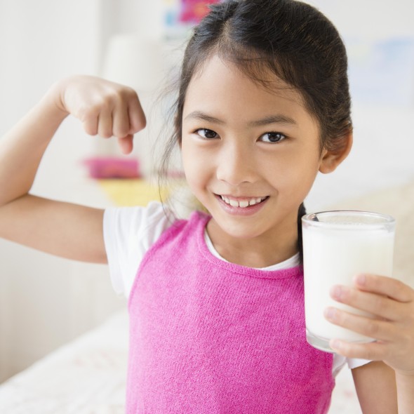 Vietnamese girl flexing muscles with glass of milk