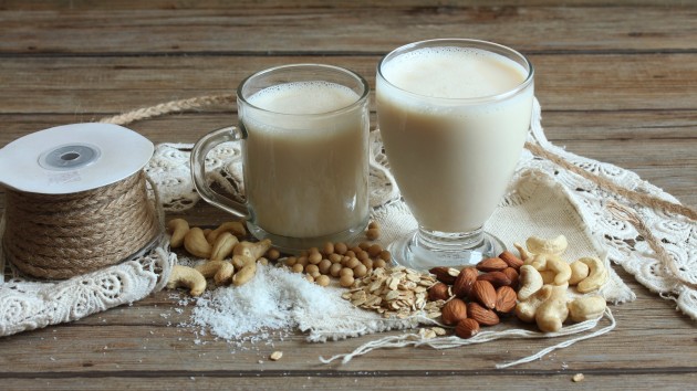 Two glasses of vegan milk, nuts, soya beans and oats