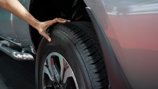 Hombre comprobando la presión de aire de los neumáticos de un coche.