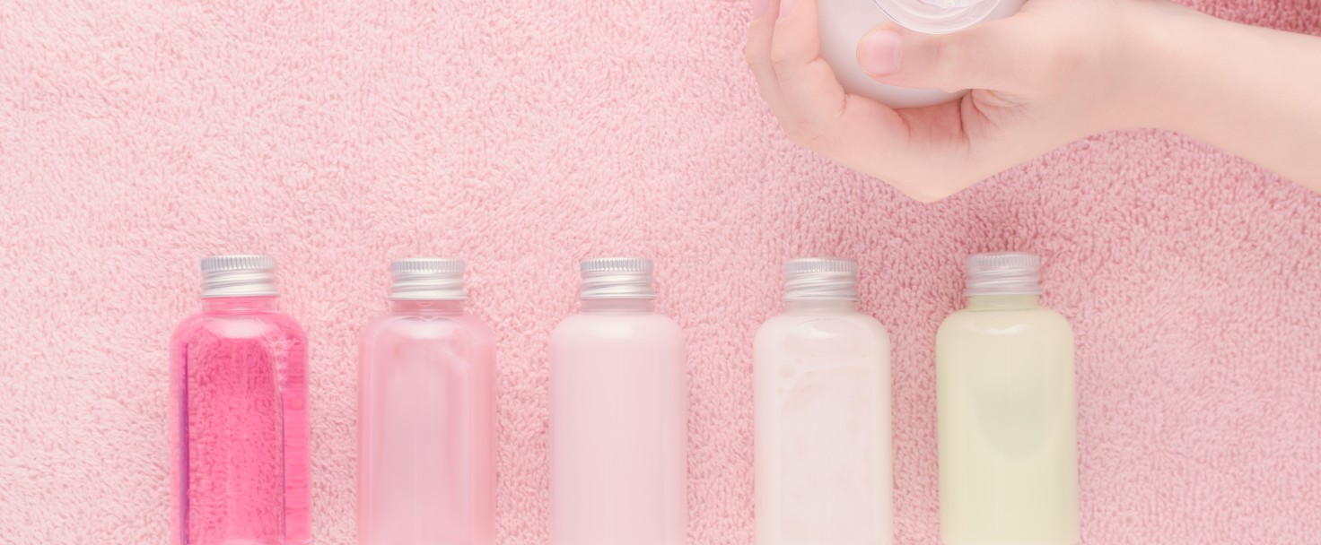 hands with a bottle and natural cosmetic bottles, shampoo, lotion, shower gel and other products, above