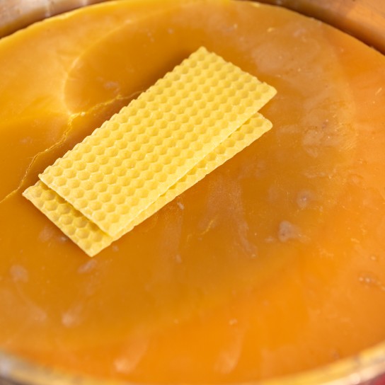 Honey beewax in bucket and plates of beeswax  as close up