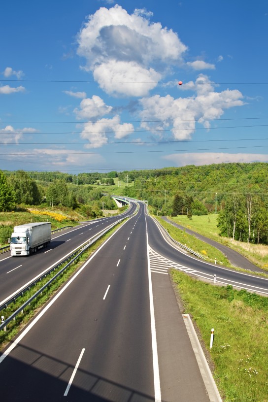 Zufahrtsstraße zur Asphaltstraße zwischen Wäldern und Feldern