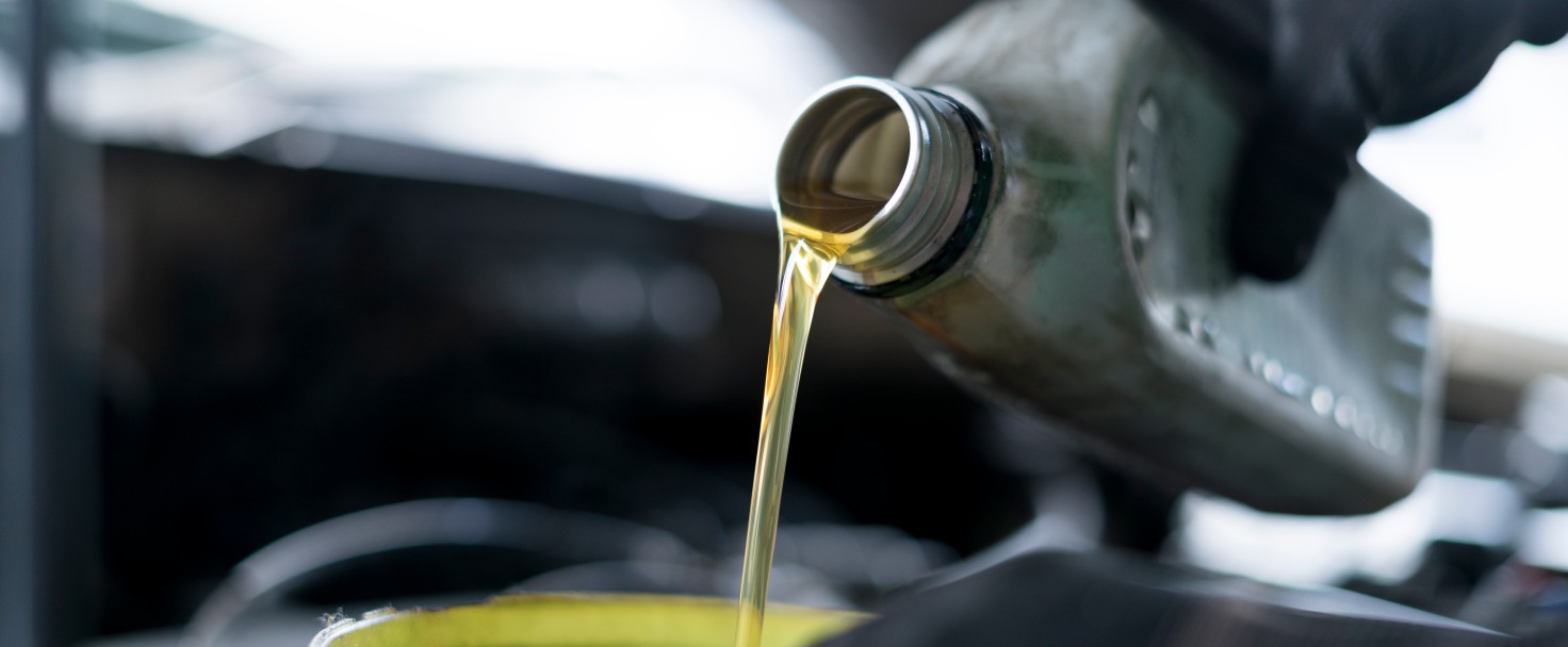 Close up of hand car mechanic refueling and pouring oil fill the oil in the engine, maintenance, and performance in auto repair shop.