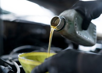 Close up of hand car mechanic refueling and pouring oil fill the oil in the engine, maintenance, and performance in auto repair shop.