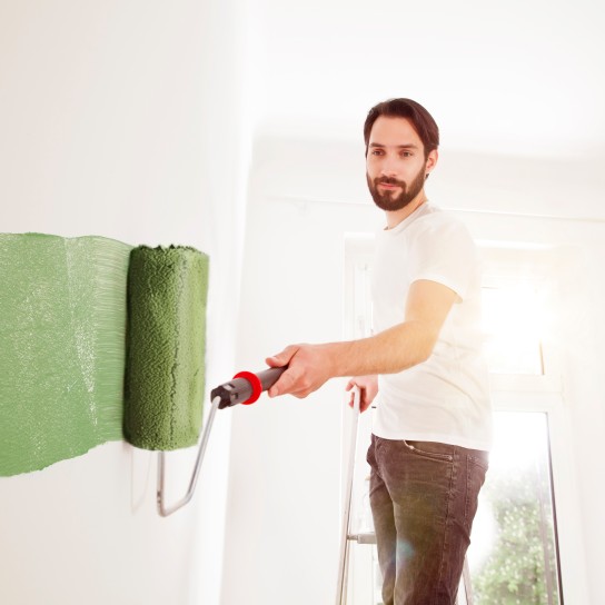Young man painting a wall green
