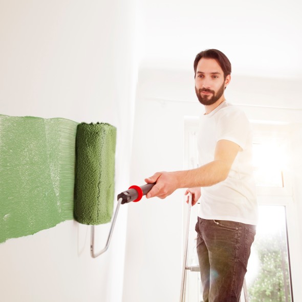Young man painting a wall green