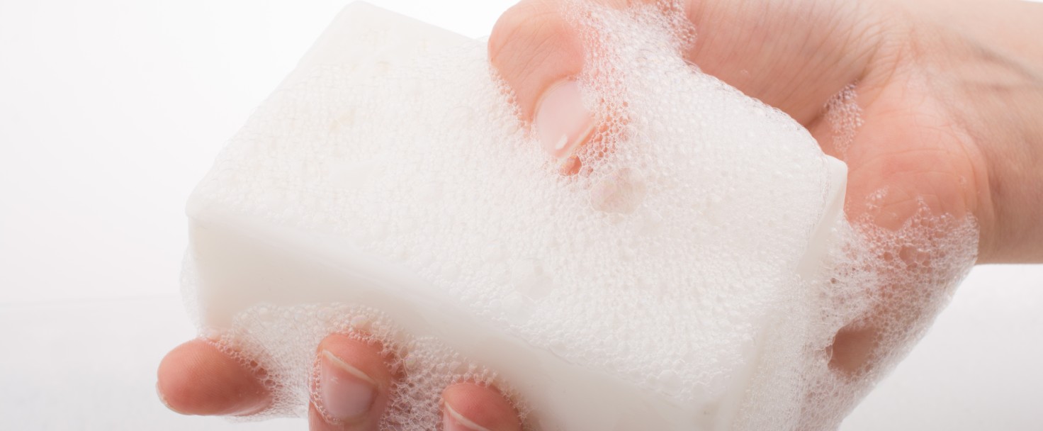 Close-Up Of Hand Holding Soap Against White Background