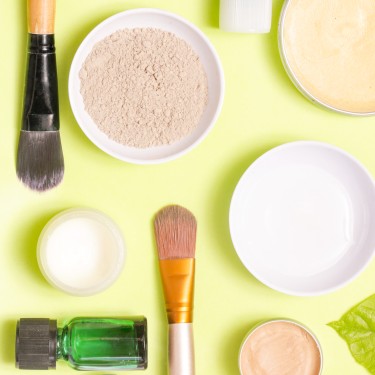 Top view of different cosmetics products on yellow background