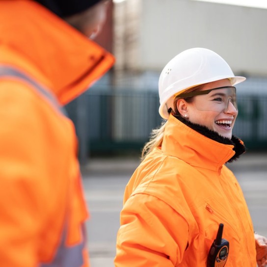  talking with a worker at the shipyard. Two commercial dock workers in reflective uniform.