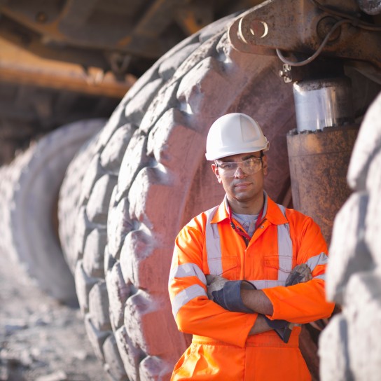 Portrait-of-miner-standing-next-to-dumper-truck-tyresin-open-cast-coalmine