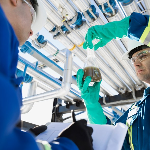 Engineers testing recording liquid in beaker gas plant