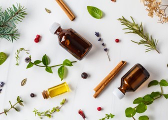 Ingredients for essential oil. Different herbs and bottles of essential oil, white background, flatlay.