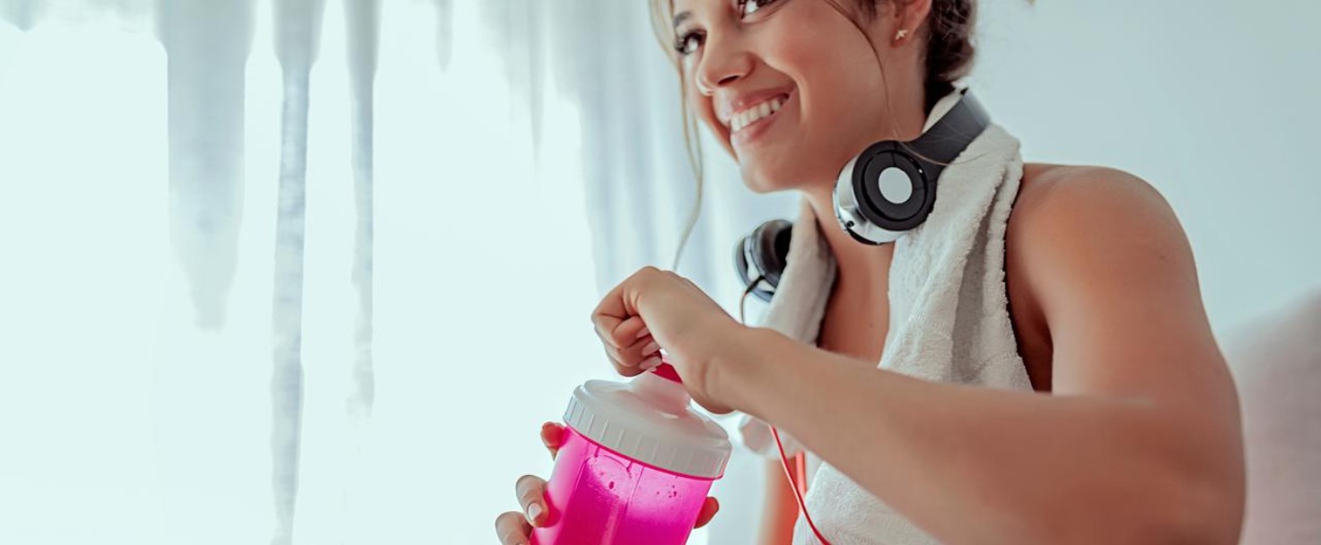 Close up Image of Young Fitness Woman With Headphones Drink Protein Shake While Sitting in Her Living Room After Workout. Young sporty woman athlete in sportswear sitting, drinking protein cocktail from shake
GettyImages-1043755718.jpg