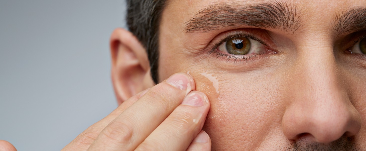 Man putting anti wrinkle gel around the eyes