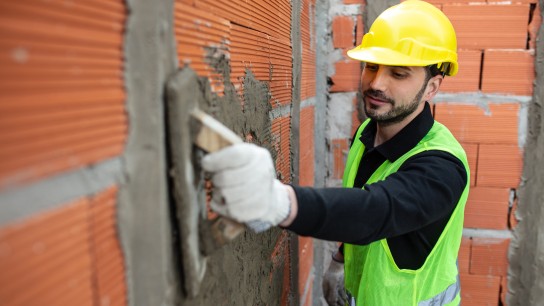 Mason worker plastering brick wall