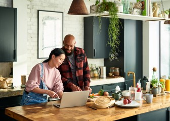 Smiling couple preparing food and using laptop, following recipe online, teamwork, food preparation
GettyImages-1386163328.jpg